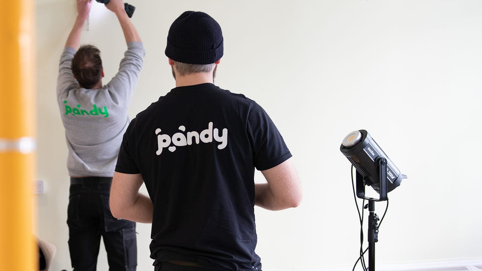 Two Pandy handymen measuring and marking where to drill holes in a wall