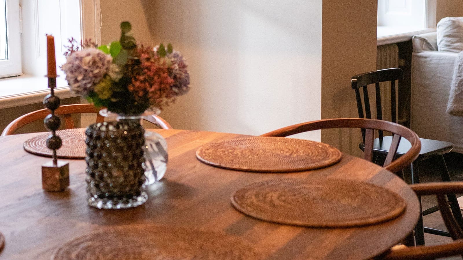 Close-up of a round walnut dining table in a bright room, nicely decorated and freshly cleaned
