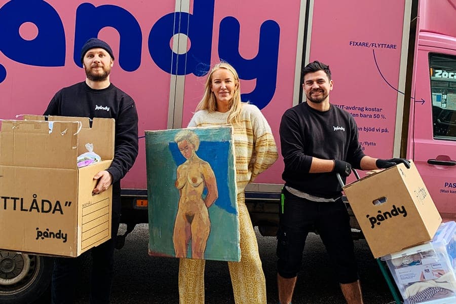 Two Pandy movers and a customer with moving boxes and a painting in front of the truck