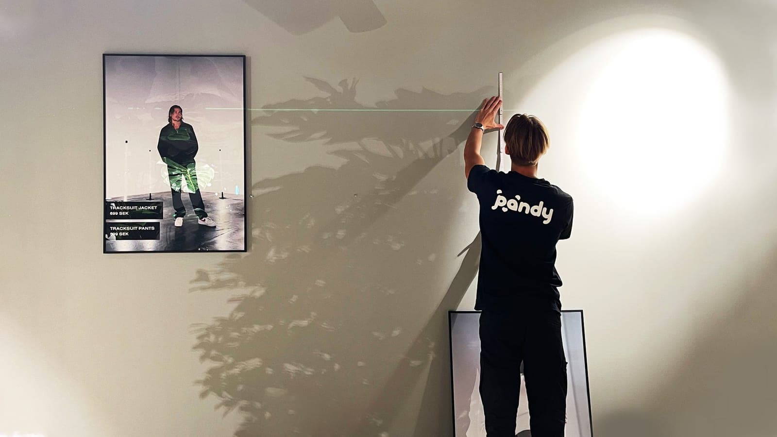 Pandy handyman measuring with a laser to hang a picture on the wall