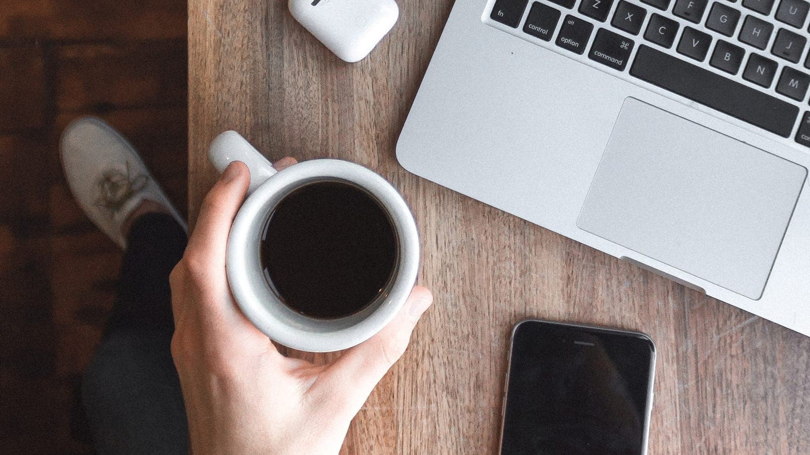 Coffee cup on a desk with a laptop and phone next to it