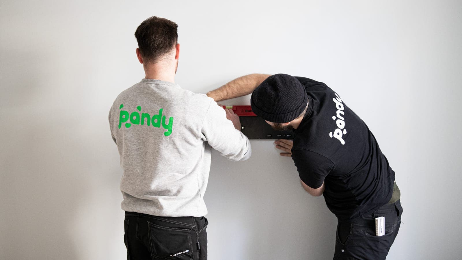 Two Pandy handymen mounting a TV on a wall