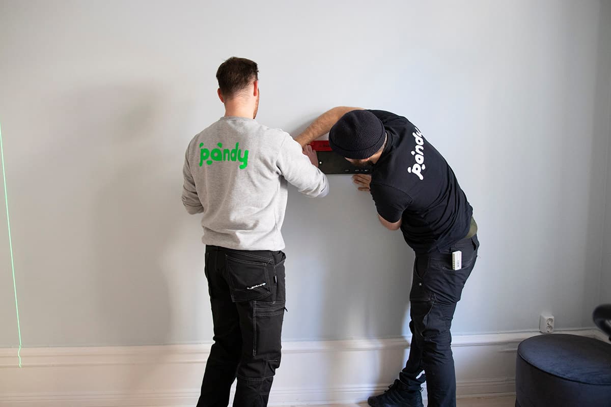Two Pandy handymen measuring a straight line on a wall with a spirit level