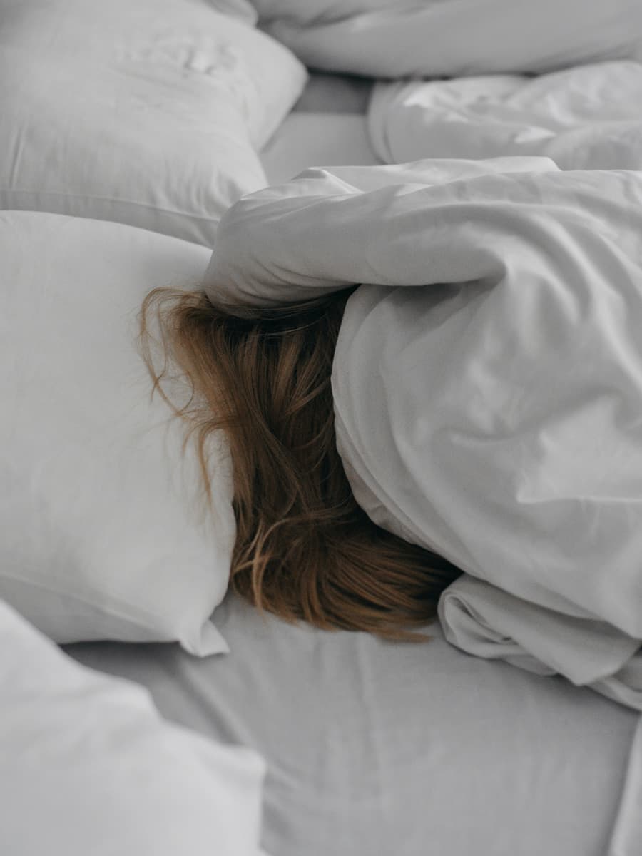 Person covering their face from the sun under the duvet