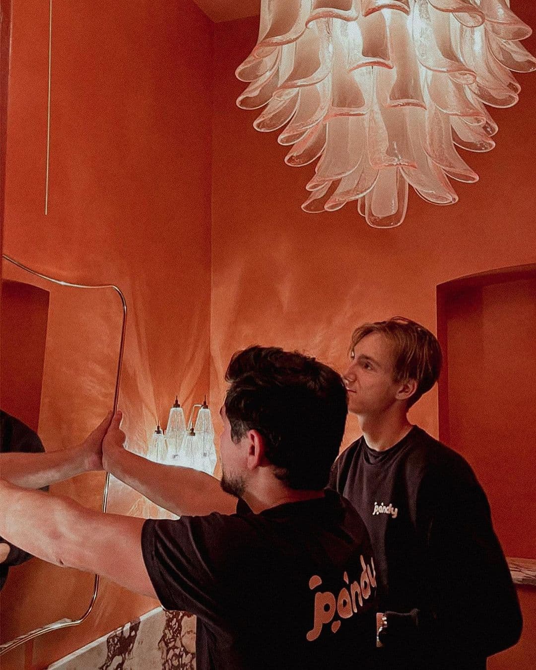 Two Pandy handymen mounting a mirror in a colourful bathroom