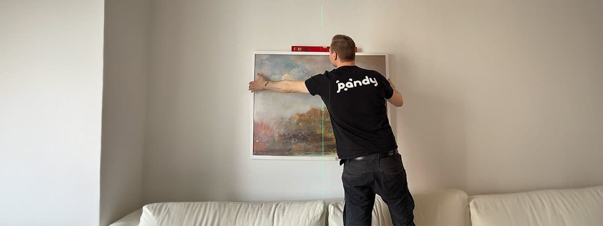 Pandy-fixare som hänger upp en tavla