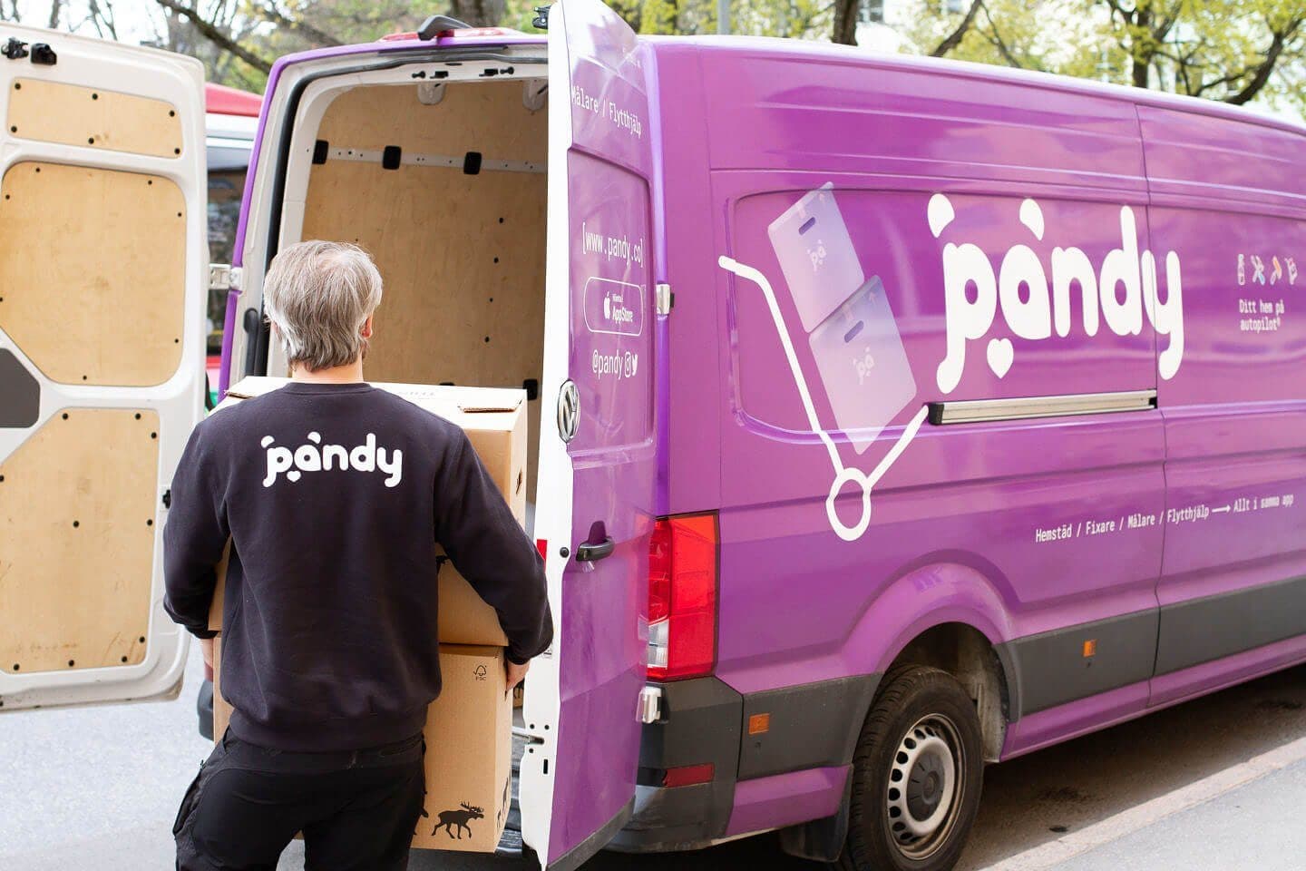Lila Pandy-skåpbil med bakdörrarna öppna och en Pandy-medarbetare med flyttlåda