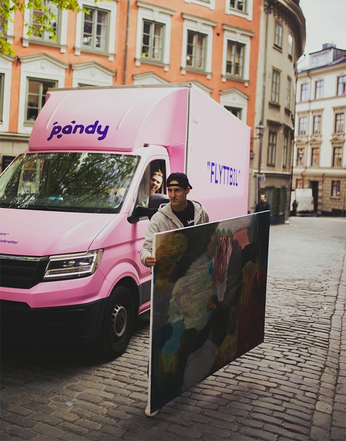Pandy mover carrying a painting in front of a pink moving van