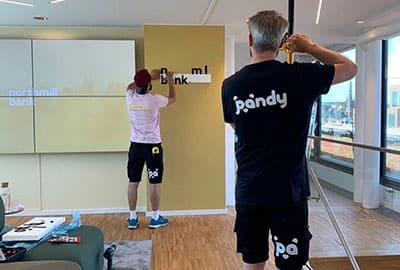 Two Pandy handymen putting up a sign at a company's office