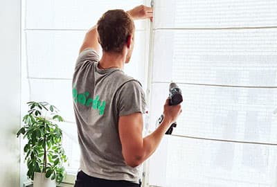 Handyman installing a curtain with a screwdriver