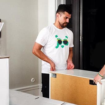 Young man in a Pandy t-shirt carrying furniture in an office